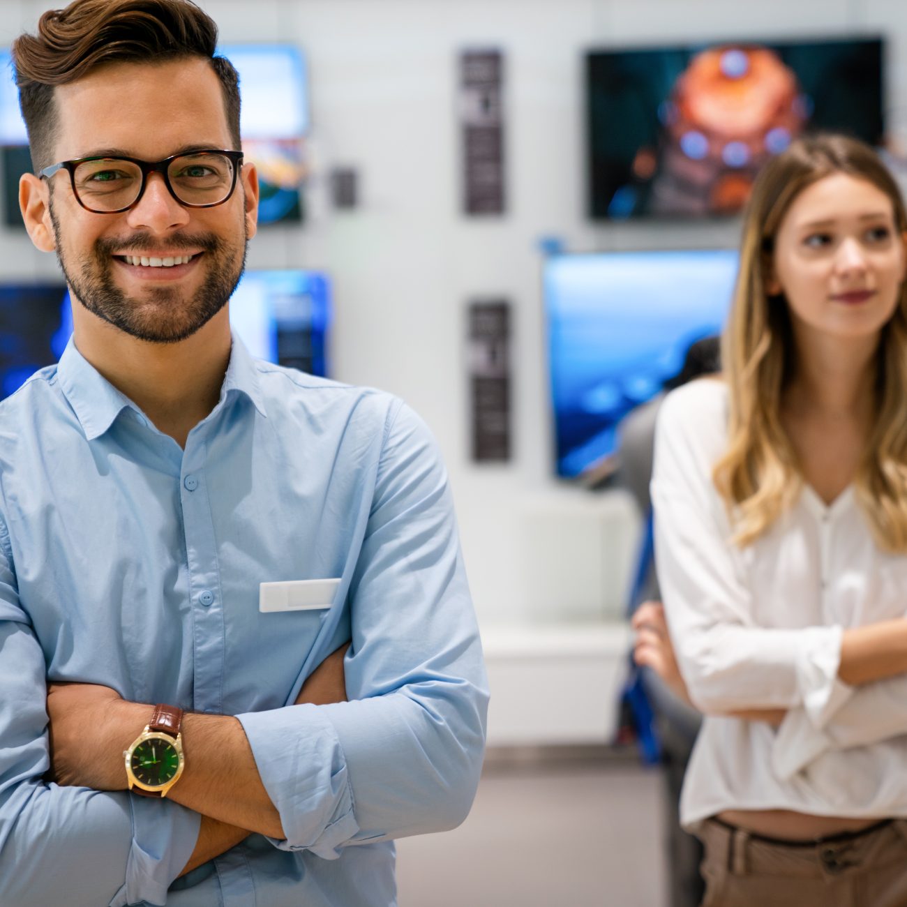 Portrait of salesman helping to woman to buy a new digital device in tech shop. Technology people concept