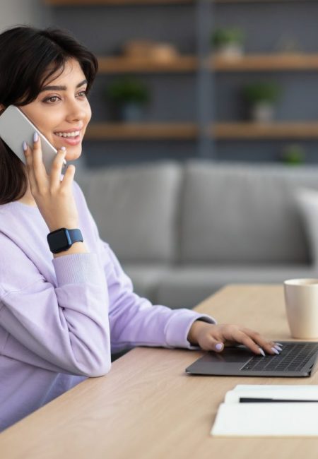 smiling-woman-working-and-talking-on-phone-at-home.jpg